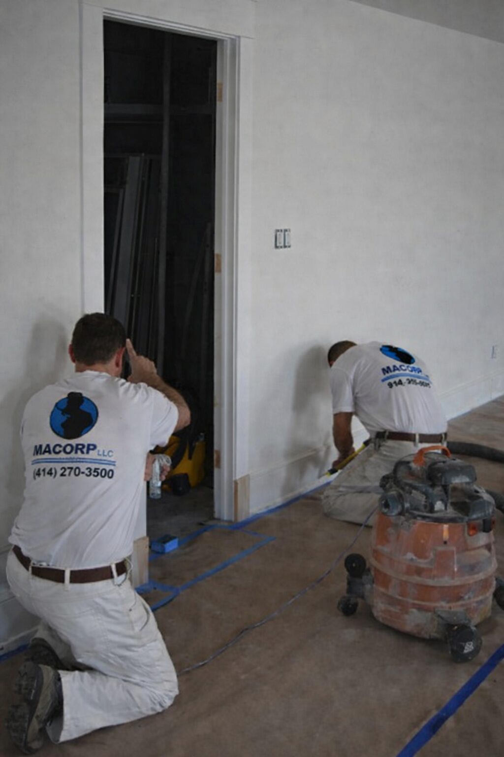 MACORP painters applying white paint to an interior wall.