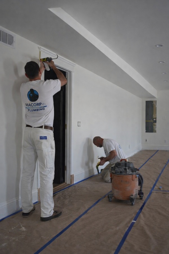 Residential wall painting with surface preparation including sanding, taping, and trim work in a modern interior space